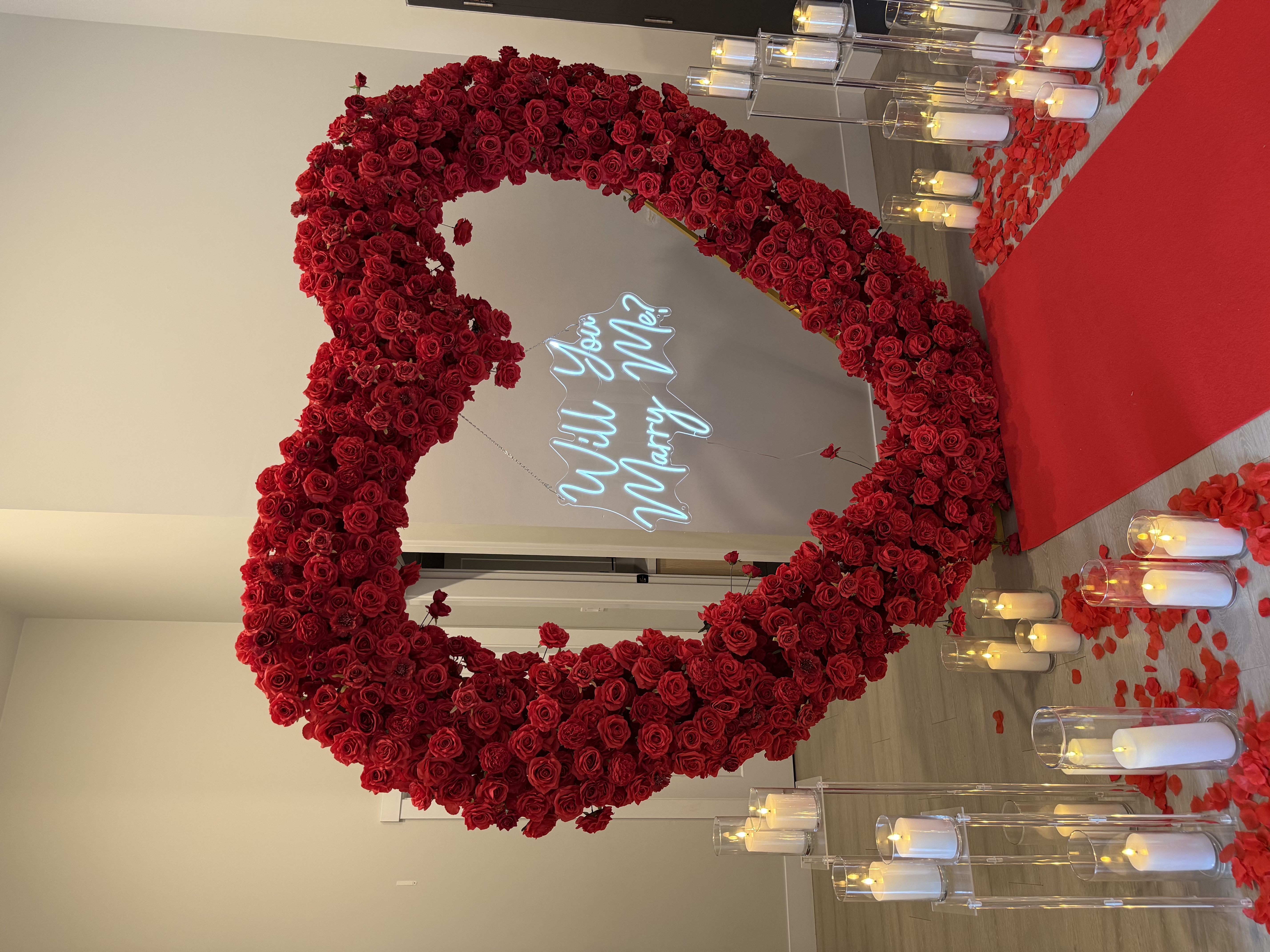 Indoor red floral heart arch with red carpet and candles