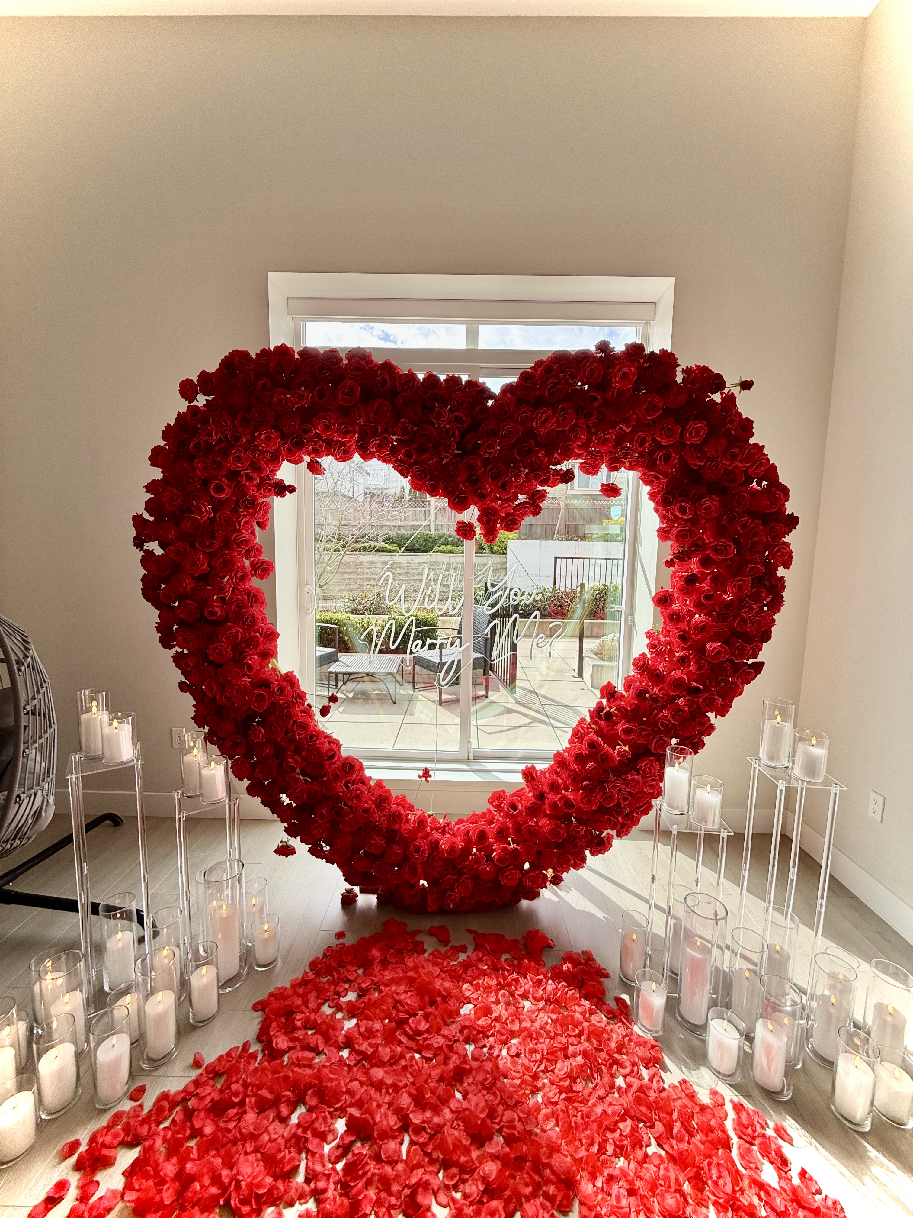 Indoor proposal with large red floral arch and candles