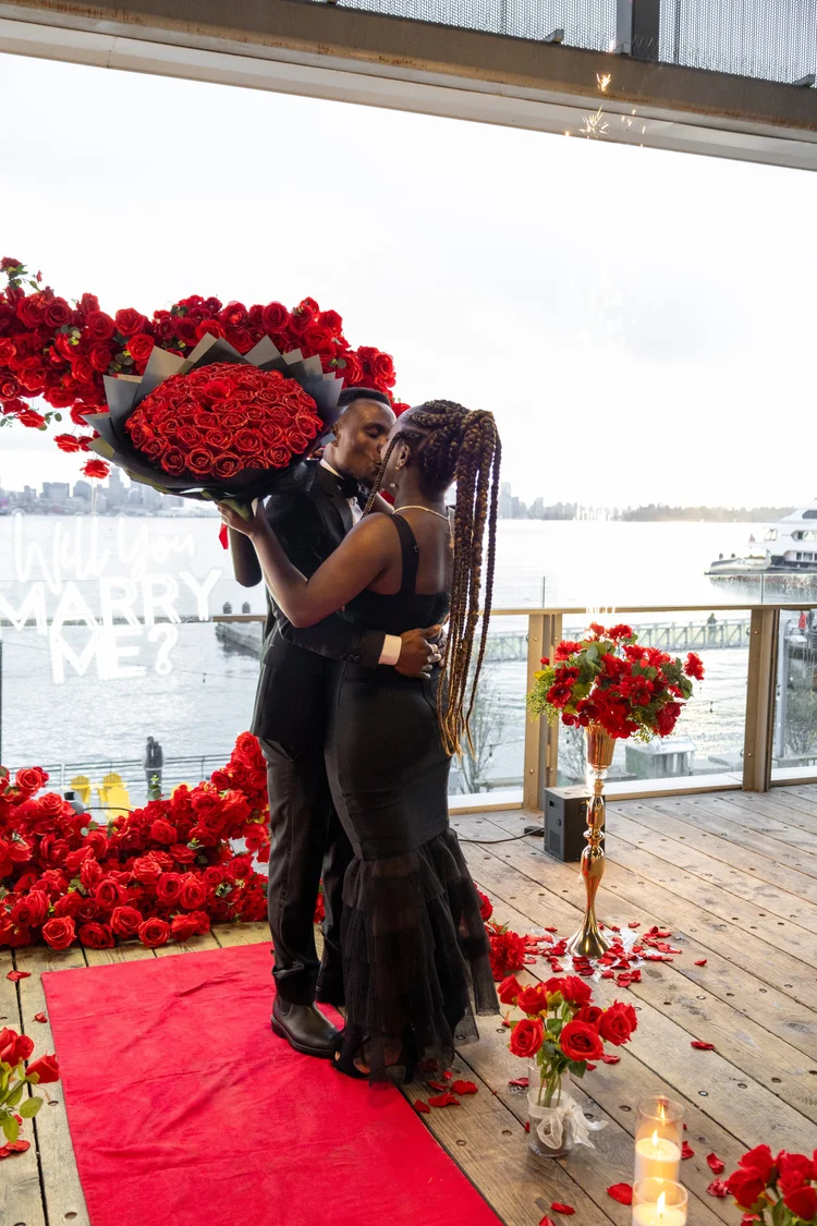 Couple kissing at red rose proposal on Vancouver waterfront